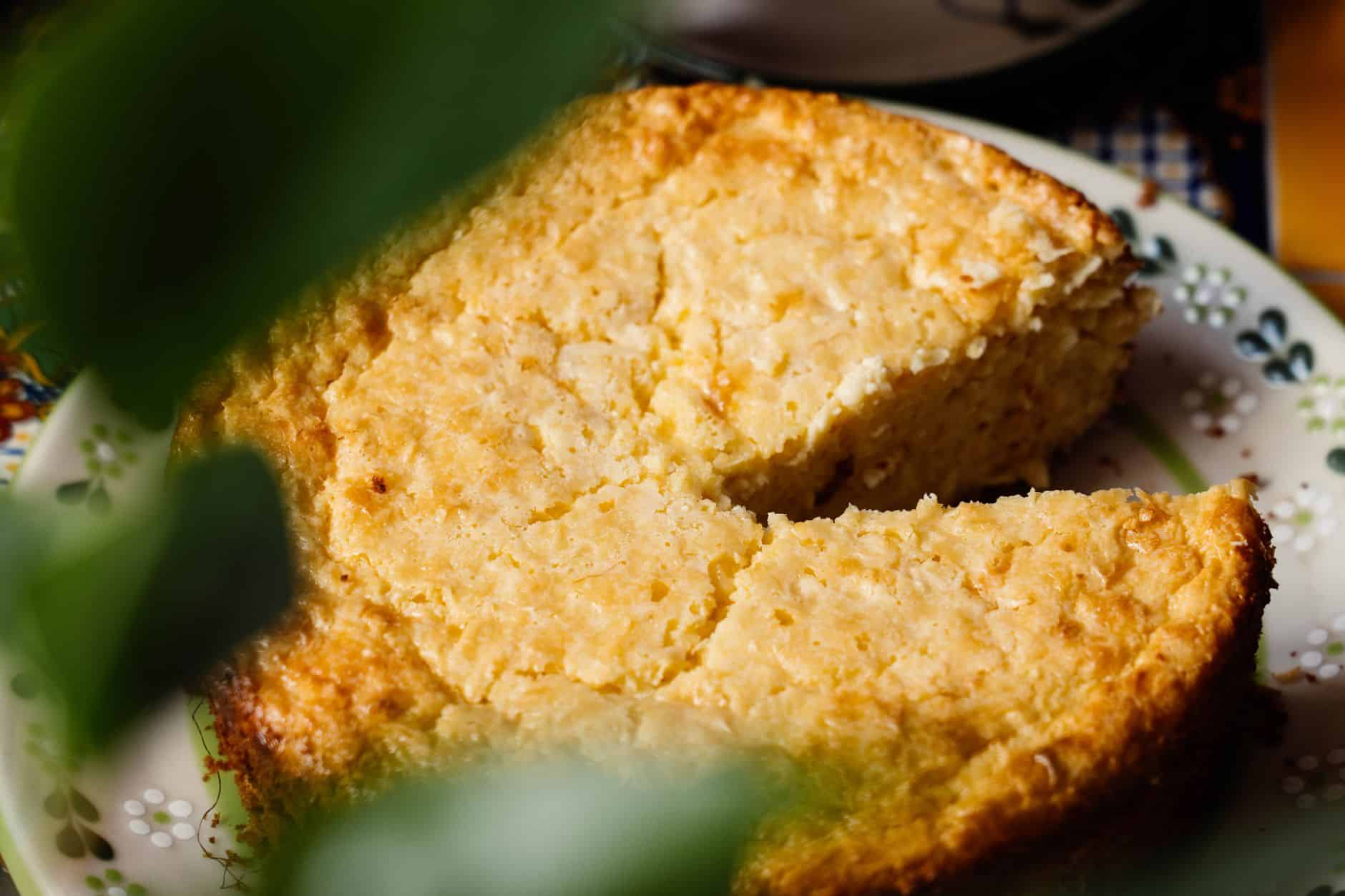 Fatia de bolo de milho cremoso dourado servida em prato branco
