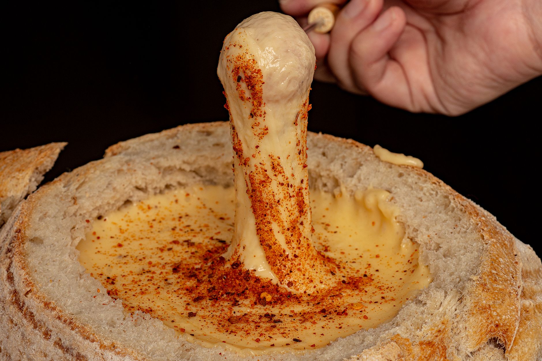 Panela de fondue de queijo derretido com pães e queijos ao redor