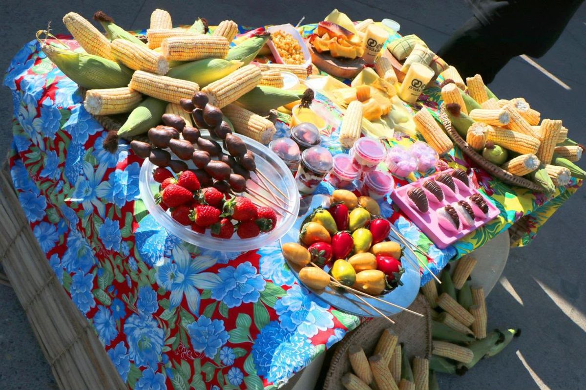 Mesa farta com espigas de milho verde, morangos do amor e frutas caramelizadas no Festival do Milho Verde de Campinas