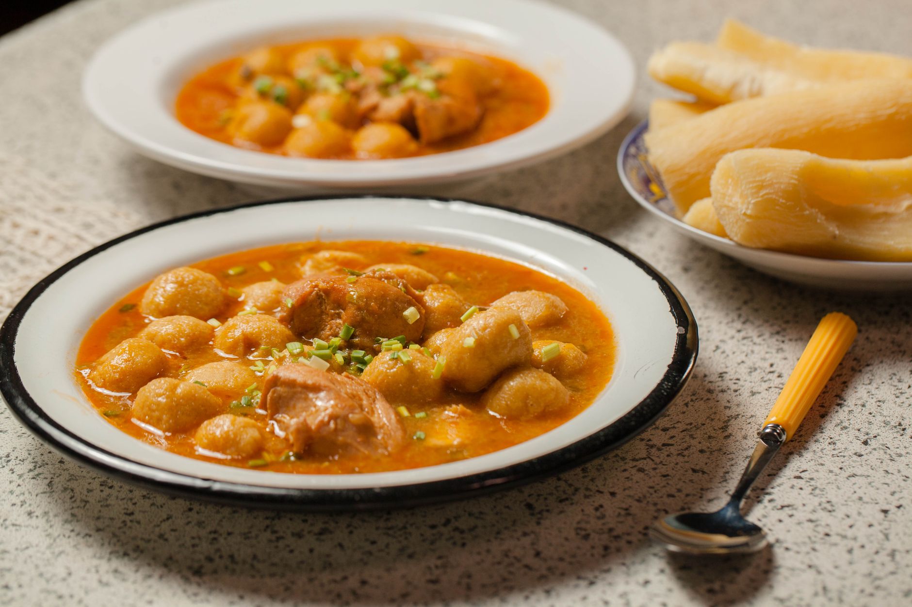 Tigela de sopa de mandioca cremosa com carne-seca desfiada e salsinha