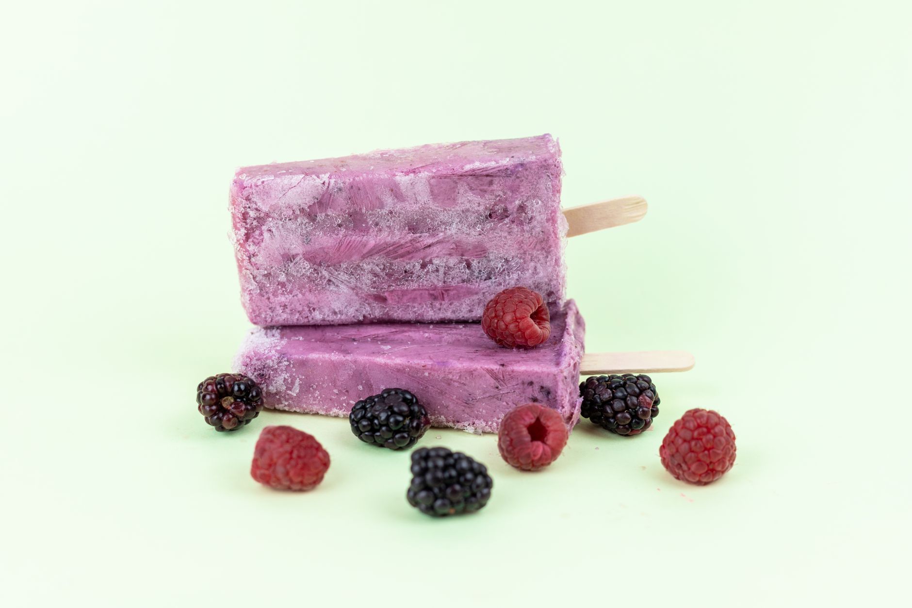 Picolés caseiros coloridos de frutas com pedaços de fruta visíveis