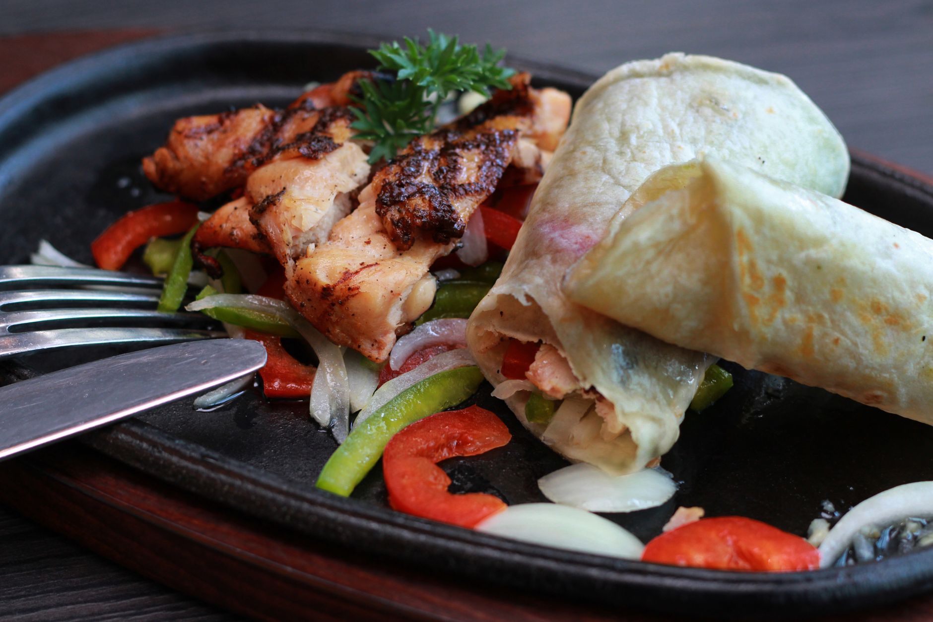 Wrap de frango recheado com folhas verdes e legumes, cortado ao meio